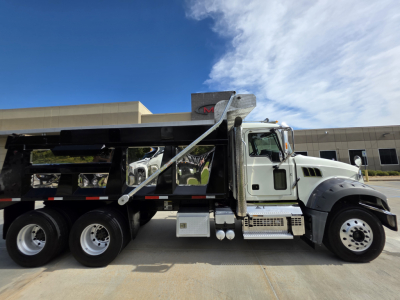 Dump truck side view showing Mack Granite with a raised dump bed and grey cab, three rear axles, chrome steps, fuel tanks, and black chassis.