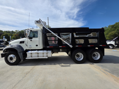 Dump truck showing Mack Granite chassis with dumped bed, side view of cab and dual rear axles.