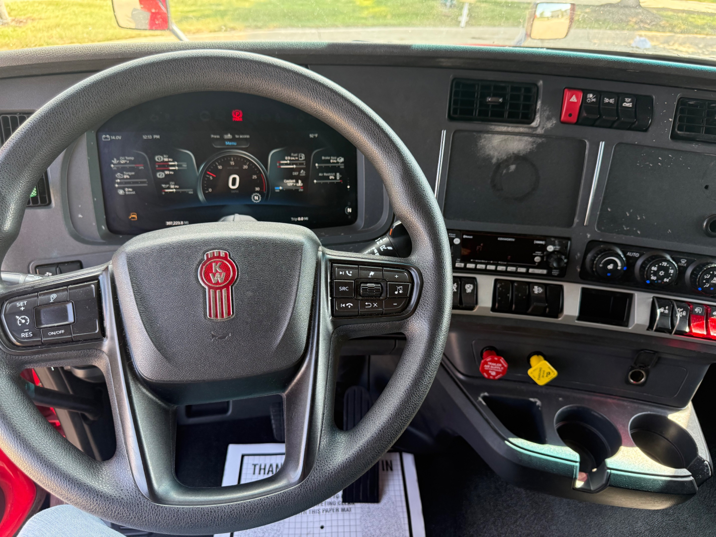 Kenworth T680 cab interior with steering wheel center, dashboard gauges, and control panels showing instrument cluster and various switches.