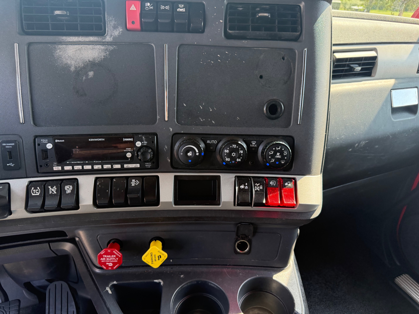 Kenworth T680 dash area showing climate controls, radio, and various switches in a used truck interior.