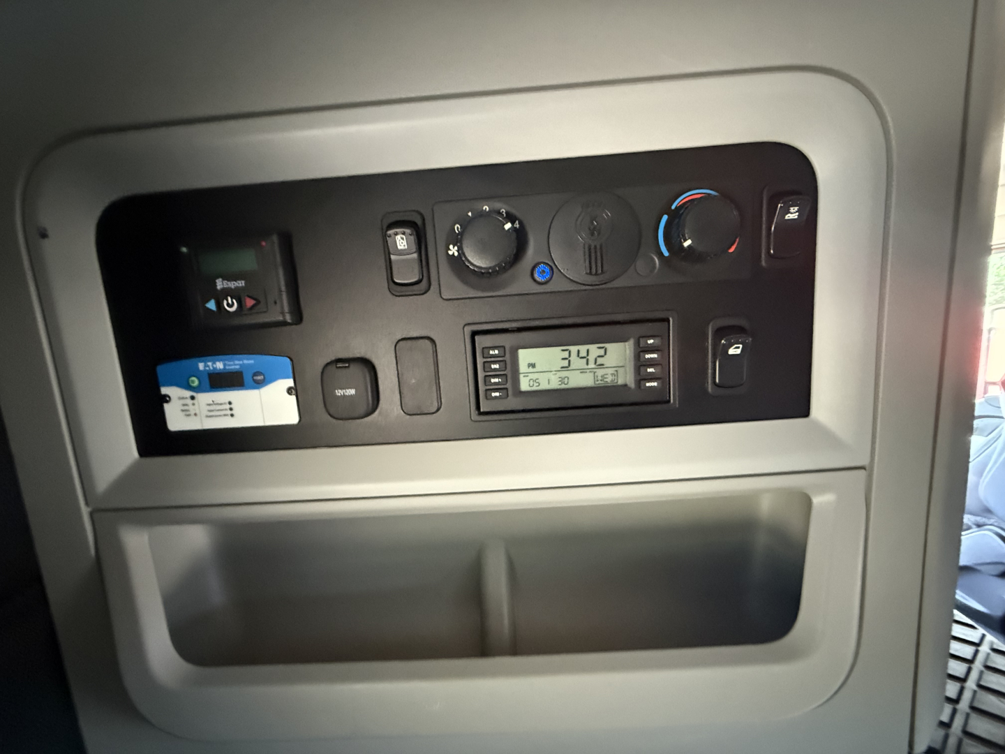 Truck cabin dashboard panel with controls and digital display showing numbers; no additional readable labels visible.
