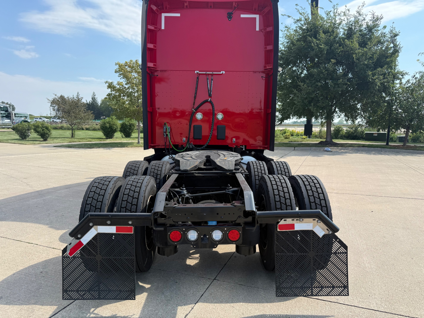 Kenworth T680 rear view showing fifth wheel and dual rear axles, mud flaps, and LED tail lights in a parking lot.