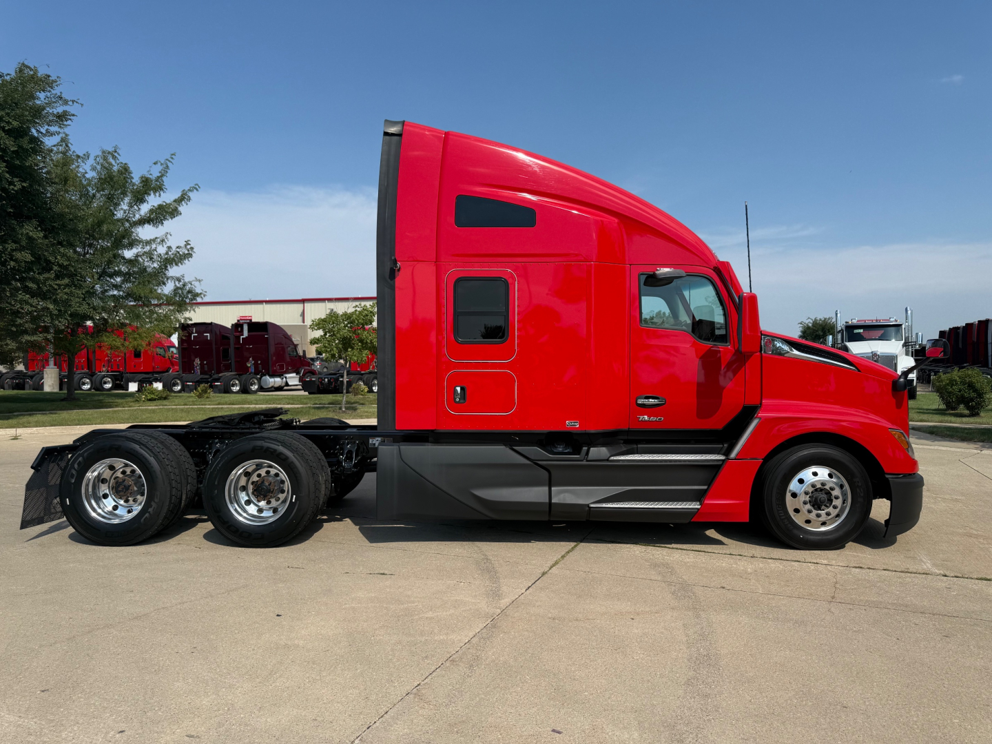 Kenworth T680 side profile showing red sleeper cab and black chassis with dual rear axles.