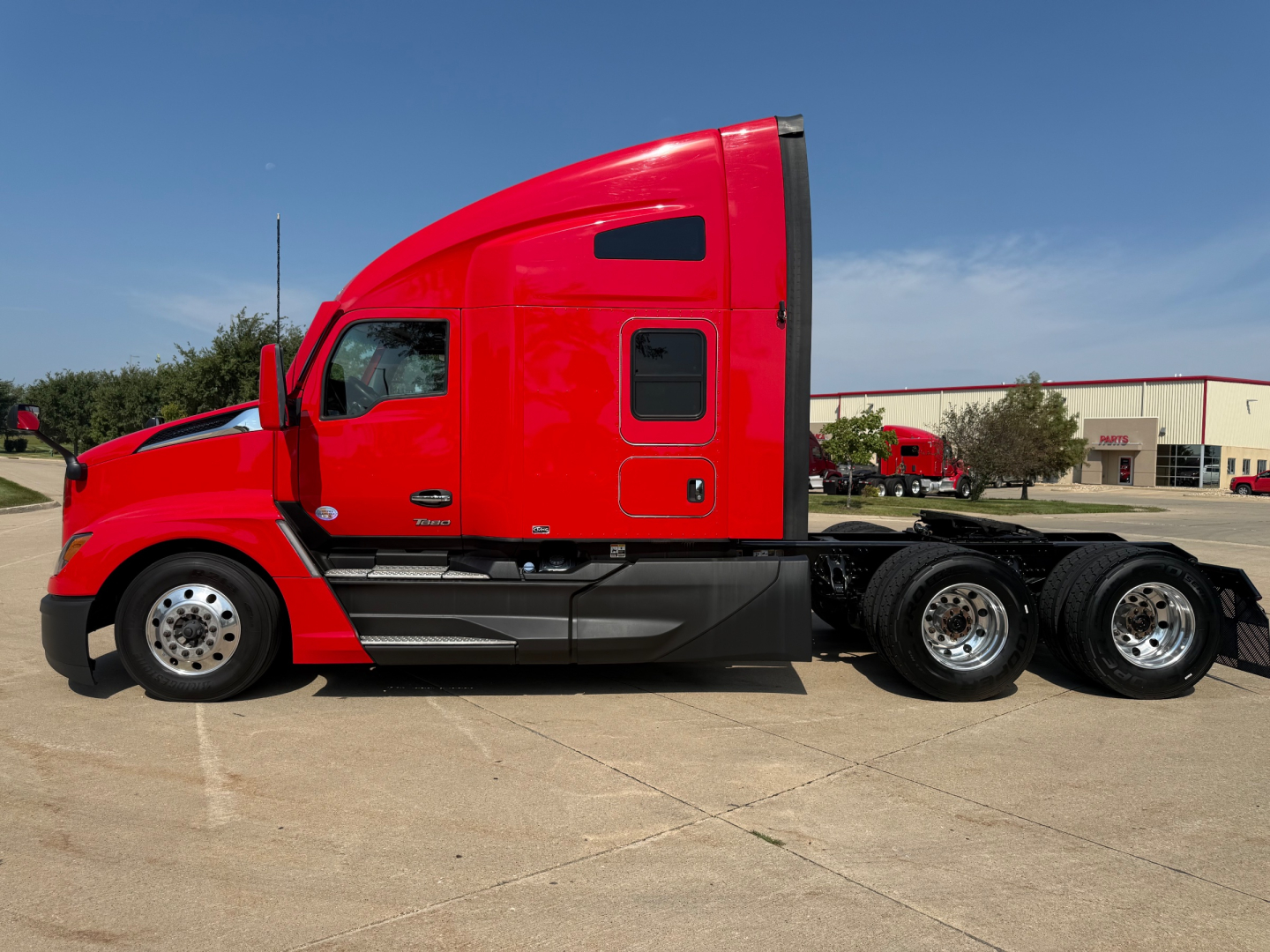Kenworth T680 tractor trailer side profile showing red sleeper cab and chrome wheels