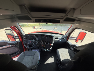 Kenworth T680 truck cab interior view with dashboard, steering wheel, and front seats visible from the driver’s side, showing instrument cluster and center console.