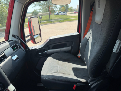 Kenworth T680 truck cabin interior showing front passenger seat, door panel, and side mirror; view through window to exterior, no cockpit controls visible.