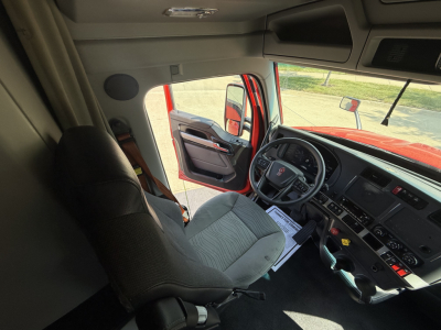 Truck cab interior of a 2024 Kenworth T680 with steering wheel, dashboard, and driver seat visible.