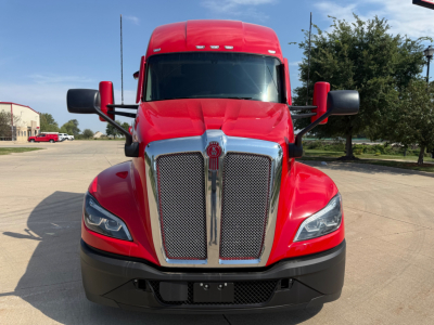 Kenworth T680 front view showing chrome grille, red cab, large side mirrors, and black bumper.