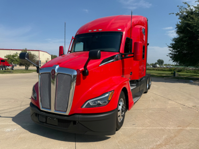 Kenworth T680 cab over view showing front grille and red exterior with black bumper and mirrors.
