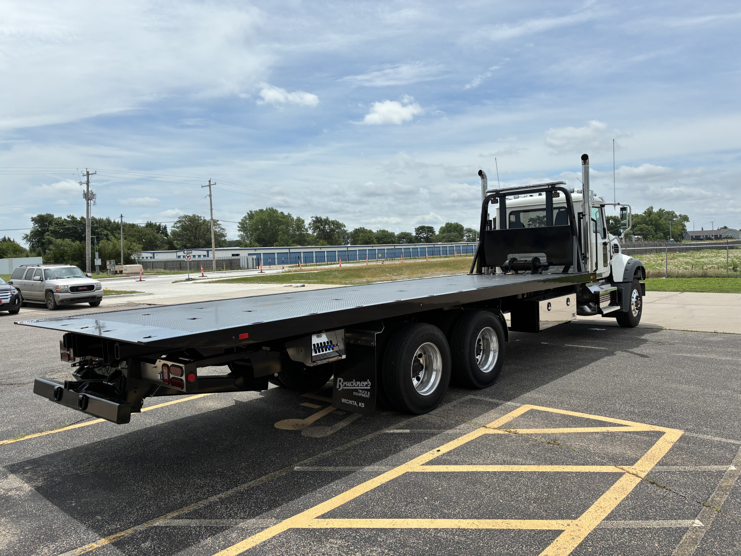 2026 Mack GR64F rollback truck showing flatbed and dual rear axles with cab and exhaust stacks.