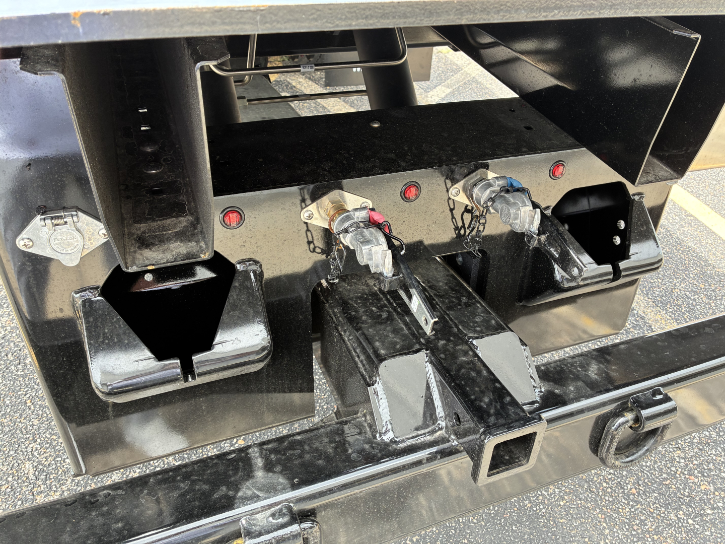 Trucks equipment hitch area showing three electrical connectors and hitch slots in a Mack rollback truck chassis.