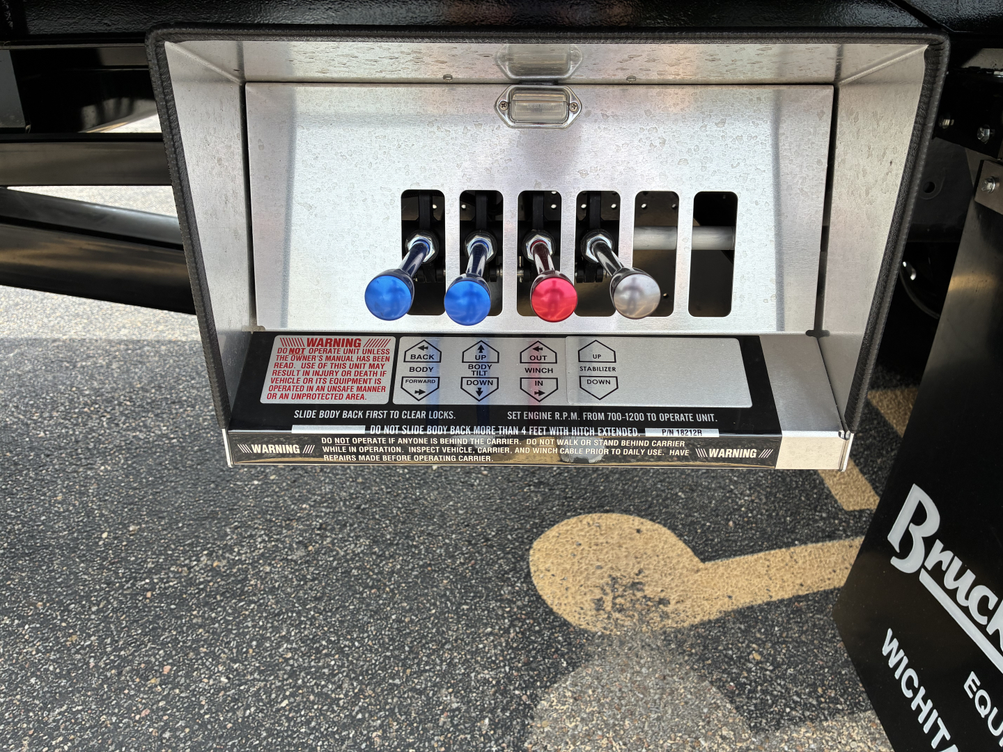 Mack GR64F rollback truck control panel with five colored levers and warning labels.