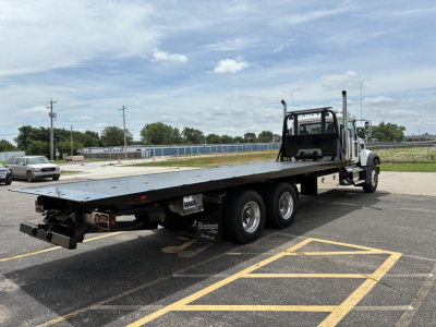2026 Mack GR64F rollback truck showing flatbed and dual rear axles with cab and exhaust stacks.