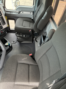 Interior of a 2026 Mack GR64F truck cab showing driver and passenger seats, dashboard, and center console.