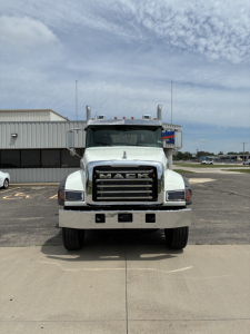 Mack GR64F truck in front view showing bold grille with 'MACK' emblem and front bumper. Clear sky, parking lot.