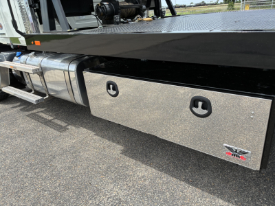 Mack GR64F rollback truck side view showing aluminum tool/storage box with two recessed handles and Mack logo.