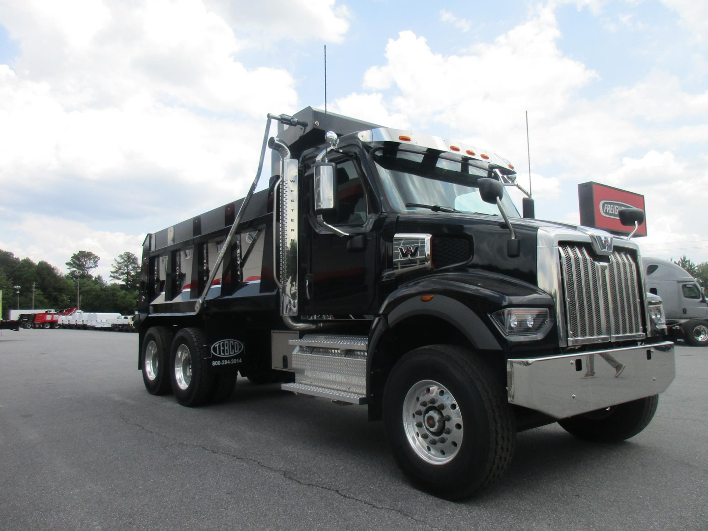 Western Star 47X dump truck in black with chrome grille and dual rear axles, front view showing cab and dump bed.