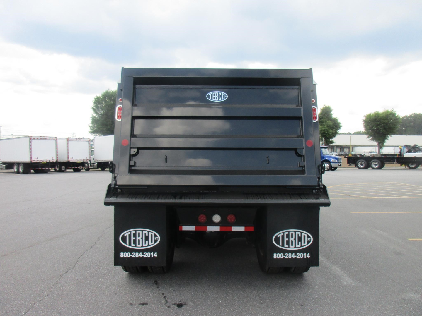 Dump truck bed of a new Western Star 47X with TEBD stickers on mud flaps and rear view showing tailgate.