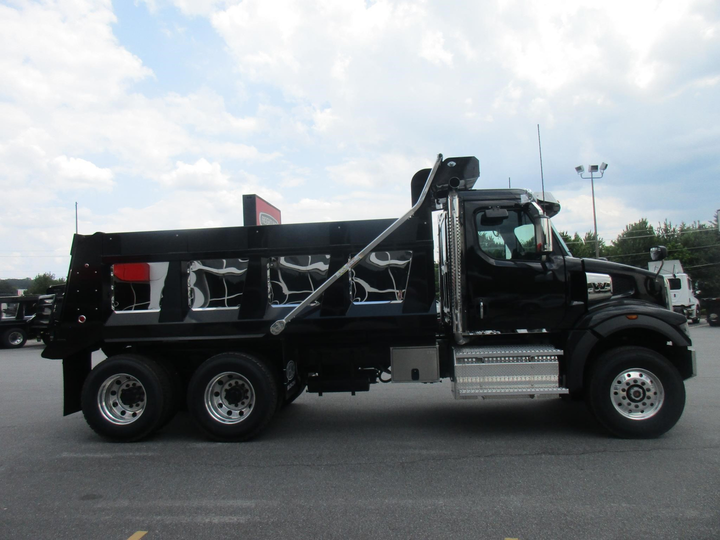 Western Star 47X dump truck side view showing black dump bed with chrome steps and dual rear axles.