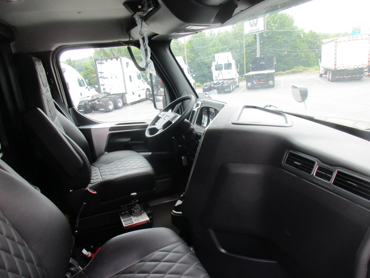 Interior cab view of a new 2027 Western Star 47X dump truck showing driver seat, steering wheel, dashboard, and center console.