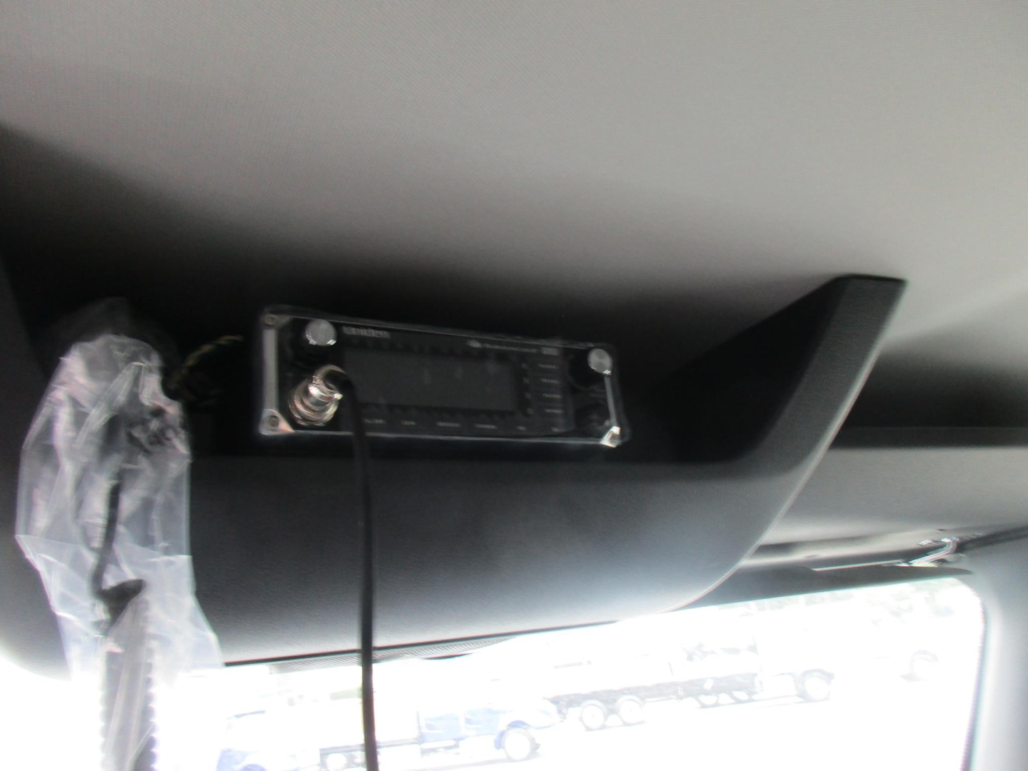 Truck interior showing a radio/monitor mounted under the dash with a cable hanging down.
