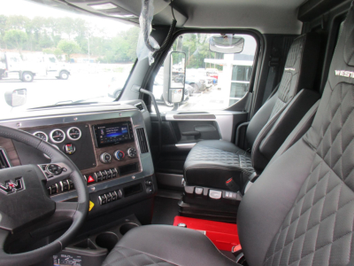 Interior of a Western Star 47X cab showing steering wheel, dashboard with gauges, touchscreen infotainment, and quilted seats.