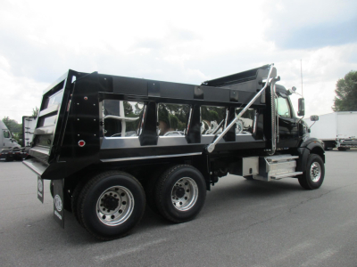 Dump truck in profile view with black dump body and dual rear axles, chrome front bumper, and hydraulic tailgate lift visible.