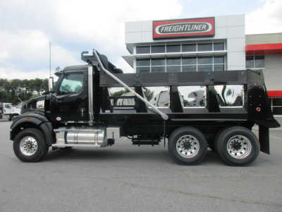 2027 Western Star 47X dump truck side view showing black dump body, chrome steps, and wheel configuration in front of a Freightliner dealership.