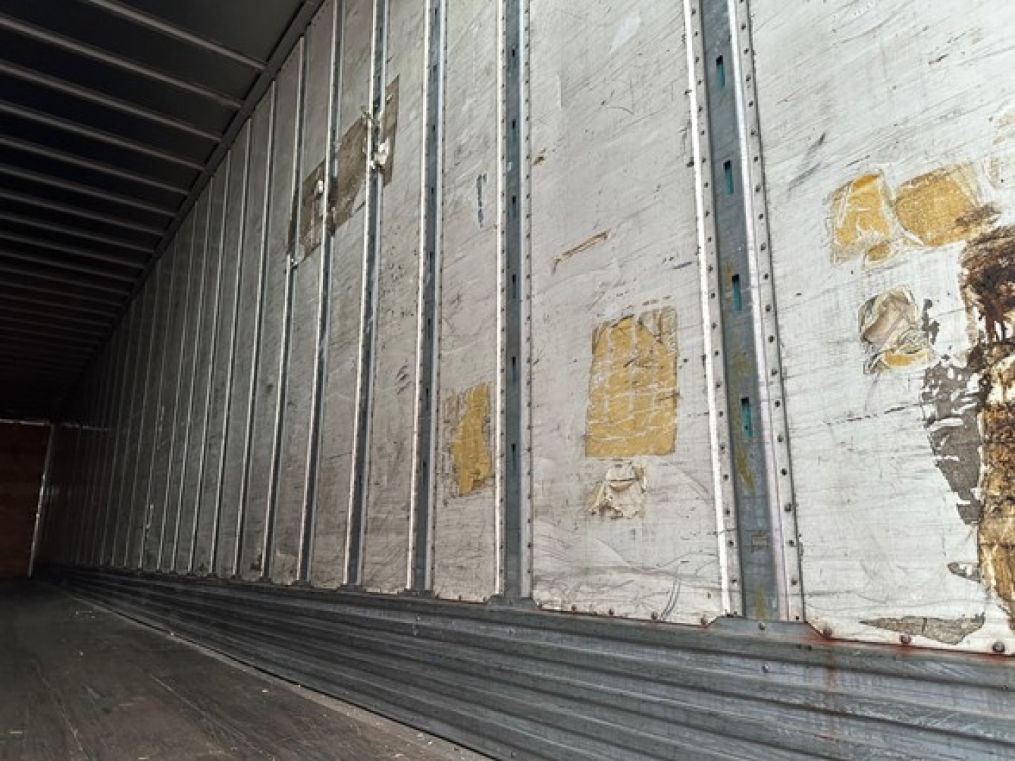 Trailer interior side wall with metal studs and worn decals visible inside a 2012 Utility 4000D-X trailer