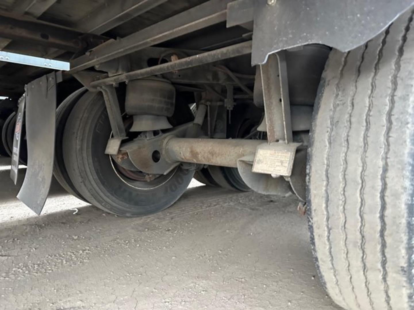 Trailer undercarriage view showing axle assembly, wheels, and leaf springs of a 2012 Utility 4000D-X trailer. Visible are the dual axles, leaf springs, and tire treads.