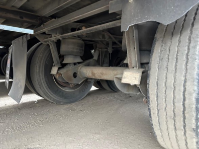 Trailer axle and undercarriage view showing dual wheels, leaf spring suspension, and drum brake components on a 2012 Utility 4000D-X trailer.