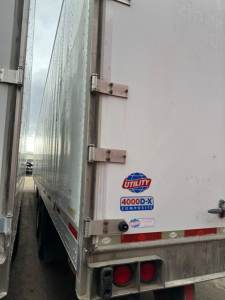 Rear right side of a Utility 4000D-X trailer showing stickered logos and latching hardware.