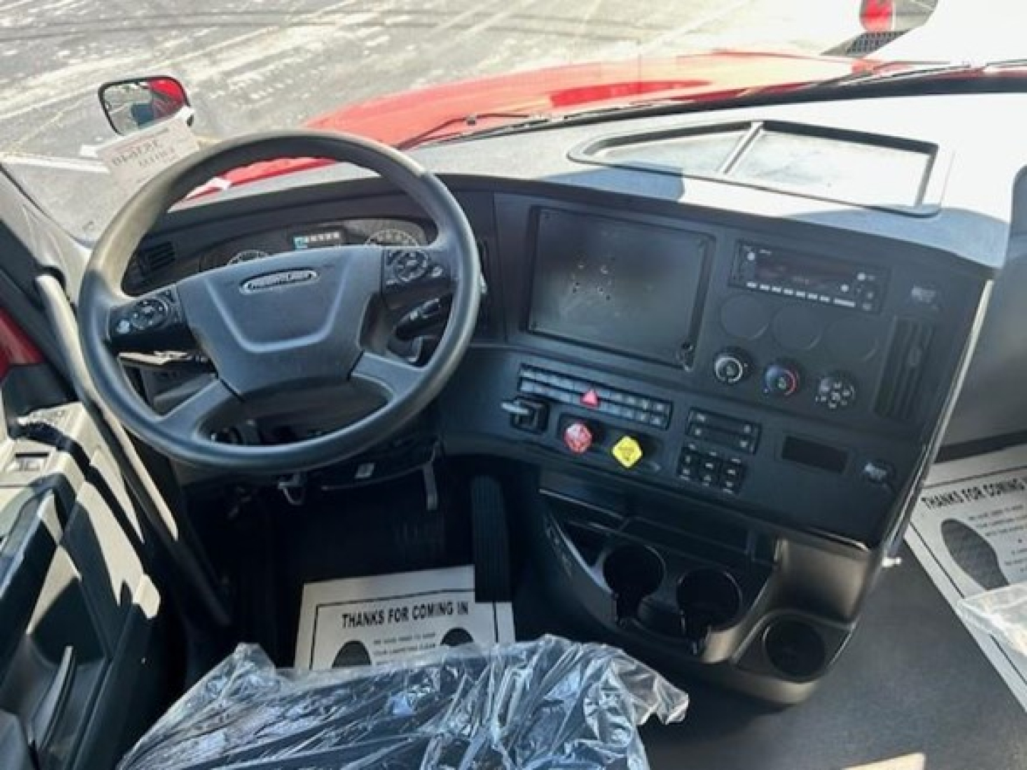 Cab interior of a Freightliner Cascadia 126 truck showing steering wheel, dashboard, touchscreen display, and center console with controls.