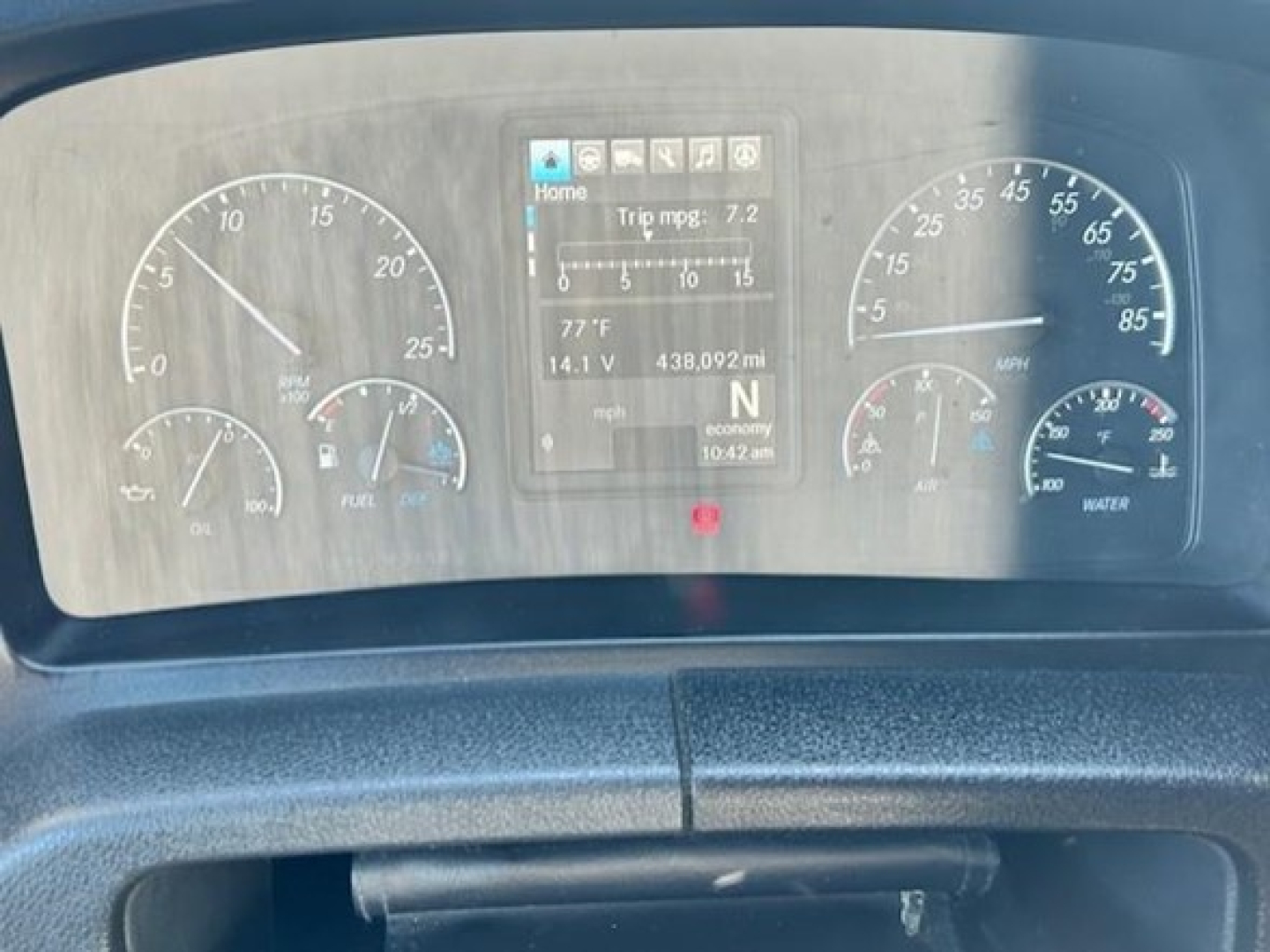 Dashboard view of 2023 Freightliner Cascadia 126 showing gauge cluster and central display with trip mpg, temperature, and speedo needles.