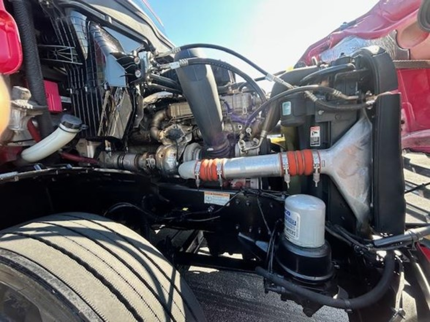 Front engine bay of a Freightliner Cascadia 126 showing hoses, radiator area, and engine components.