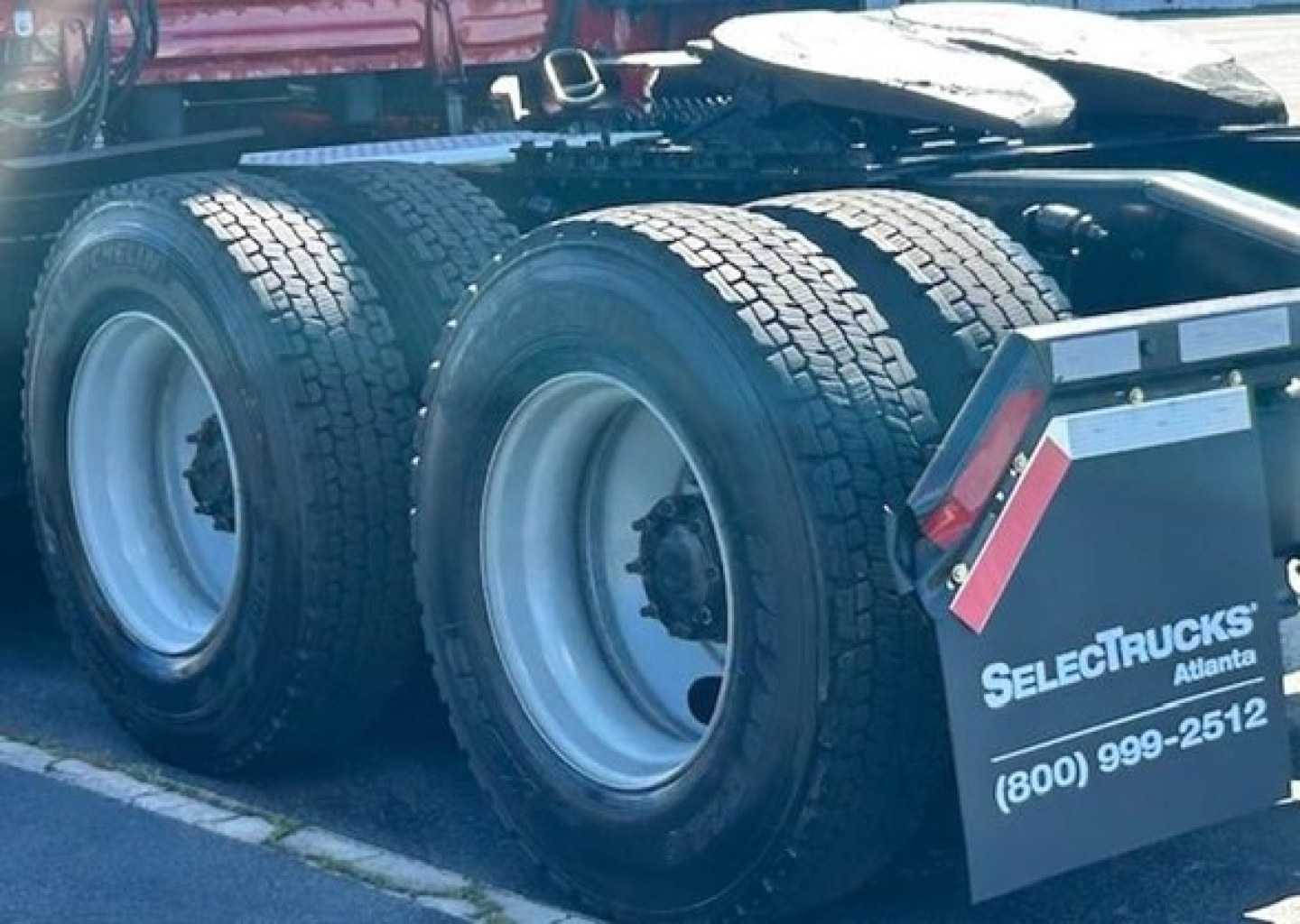 [Component] [Rear dual drive wheels] showing heavy truck tires and wheel hubs with mud flaps labeled 'SELECTTRUCKS Atlanta' and phone number.