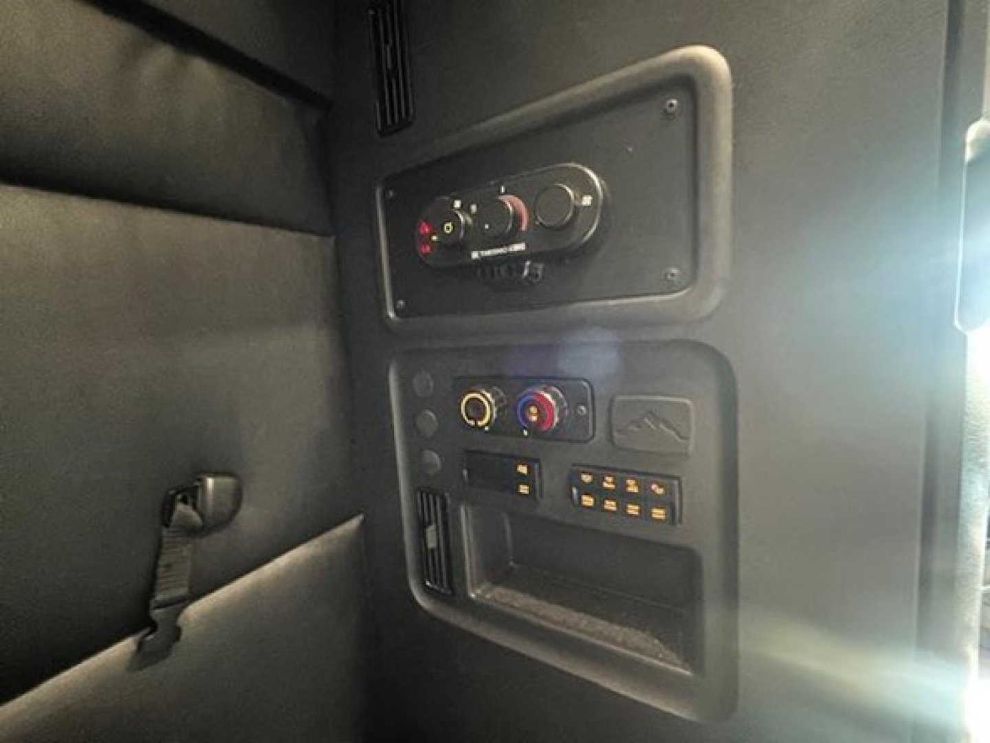 Dashboard panel of a Freightliner Cascadia sleeper cab showing climate controls, knobs, and electronic outlets.