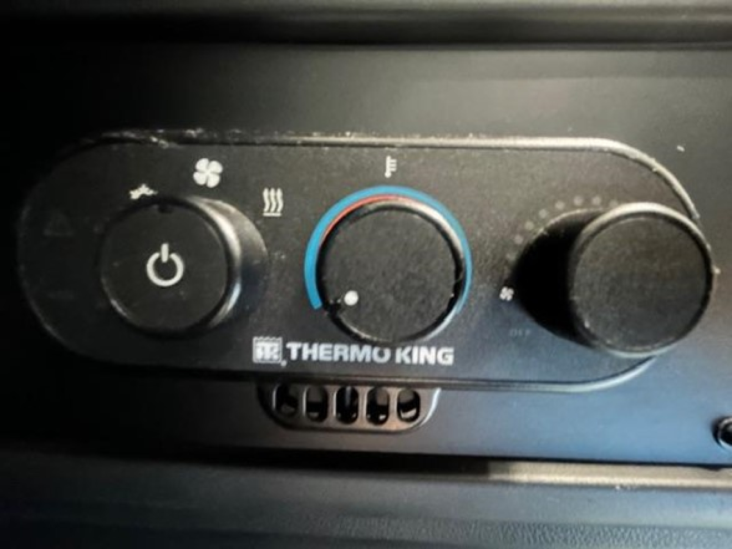 Truck cab dashboard control panel showing Thermo King climate controls with circular blue-red dial and fan icon.