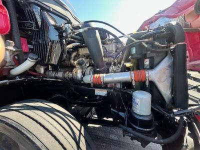 Front engine bay of a Freightliner Cascadia 126 showing hoses, radiator area, and engine components.