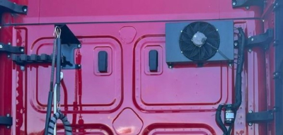 Freightliner Cascadia engine bay area with external cooling unit and pink body panel.