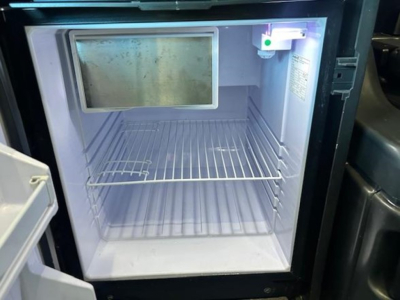 Freightliner Cascadia 126 sleeper cab interior showing compact refrigerator/freezer unit with empty freezer shelf and cold compartment.
