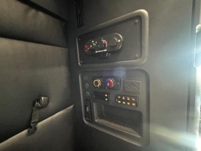 Dashboard panel of a Freightliner Cascadia sleeper cab showing climate controls, knobs, and electronic outlets.