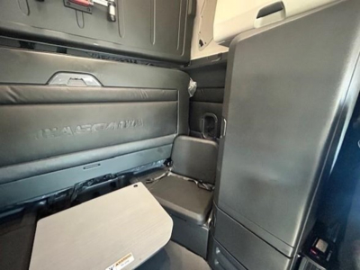 Interior of a Freightliner Cascadia sleeper cab showing storage compartments and seat area with 'FREIGHTLINER' branding visible on the side panel.