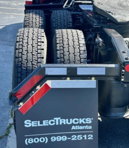 Conventional sleeper truck rear showing dual rear axles with tires and SelectTrucks Atlanta mudflap with phone number (800) 999-2512.
