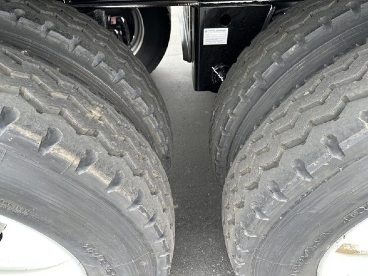 Twin rear wheels of a Smithco tri-axle side dump trailer showing rugged off-road tires and wheel hubs.