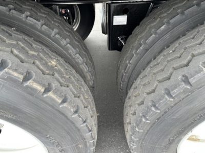 Twin rear wheels of a Smithco tri-axle side dump trailer showing rugged off-road tires and wheel hubs.