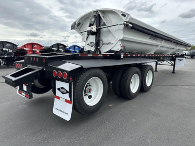 Tri-axle side dump trailer showing a large metal dump bed and multiple axles with white wheels; rear lights, mud flaps, and chassis visible; SmithCo branding on bed.