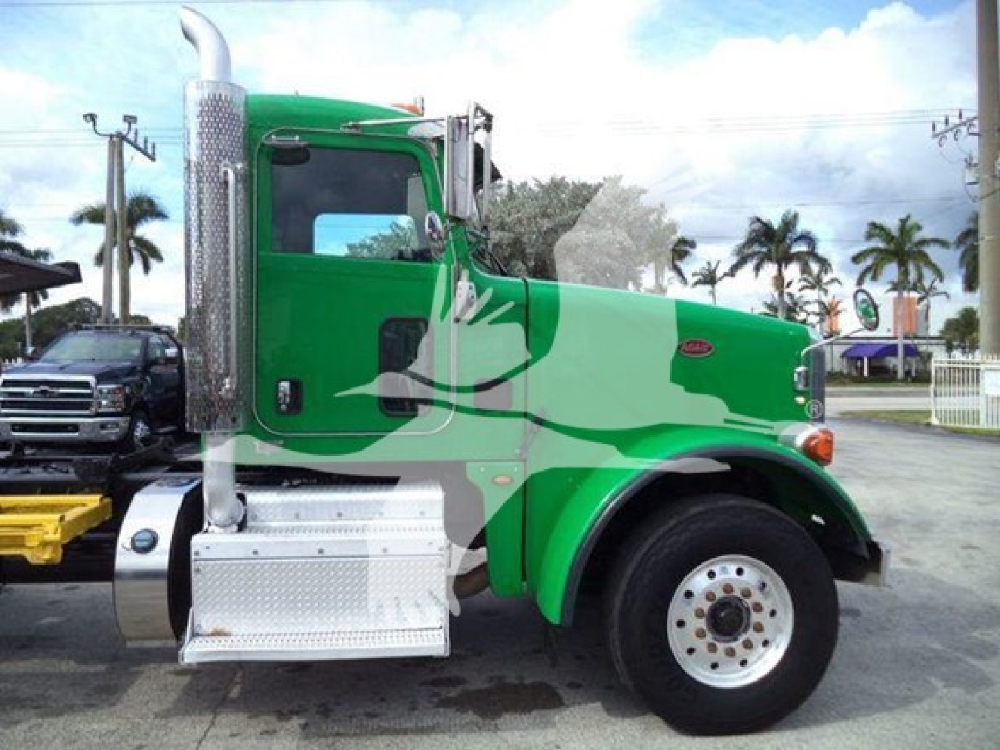 Truck cab side of a green 2014 Peterbilt 367 with chrome exhaust stack, aluminum steps, and front fender; Rollback category.