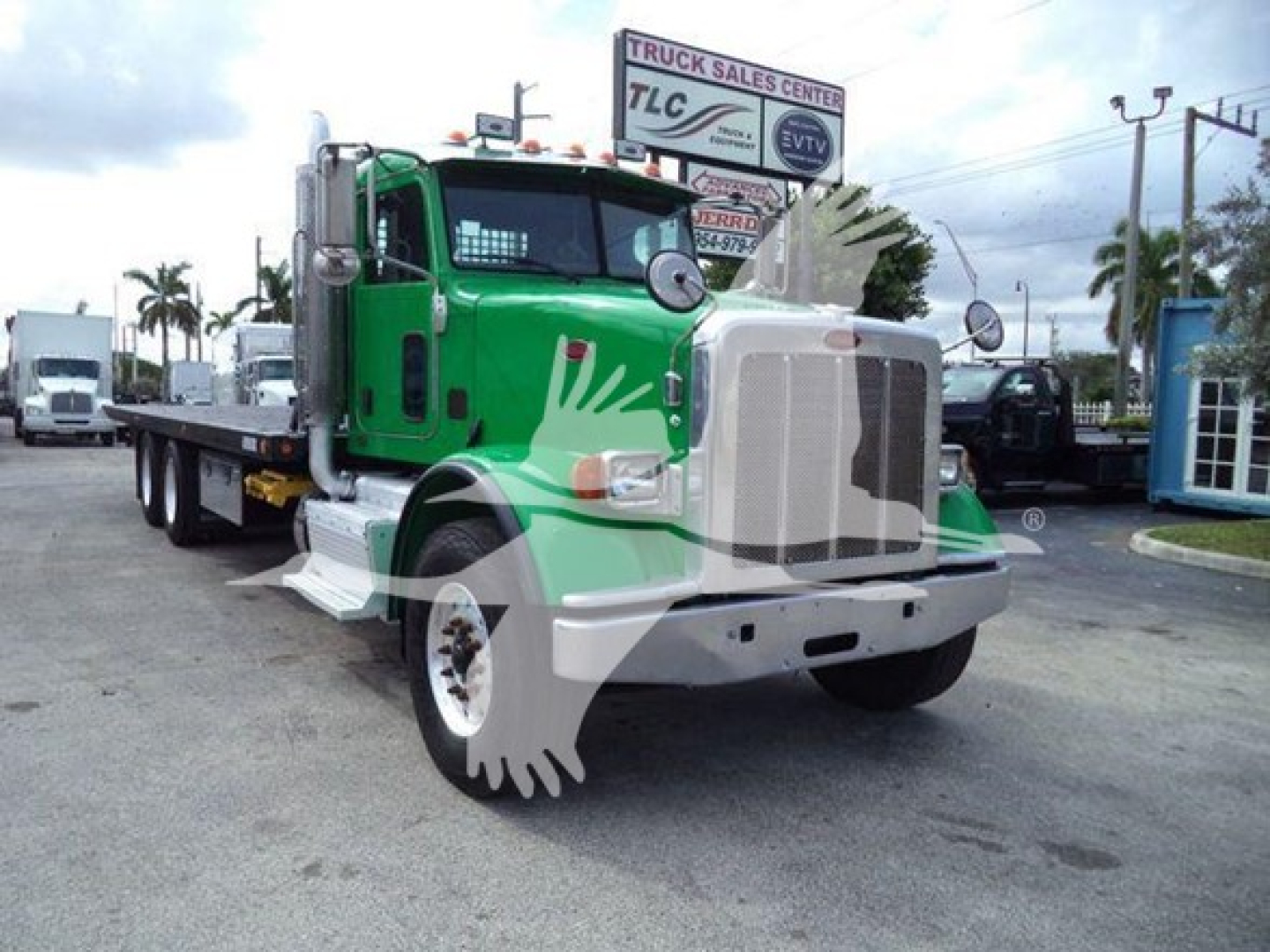 Green and white 2014 Peterbilt 367 rollback tow truck front view with chrome grille and side mirrors.
