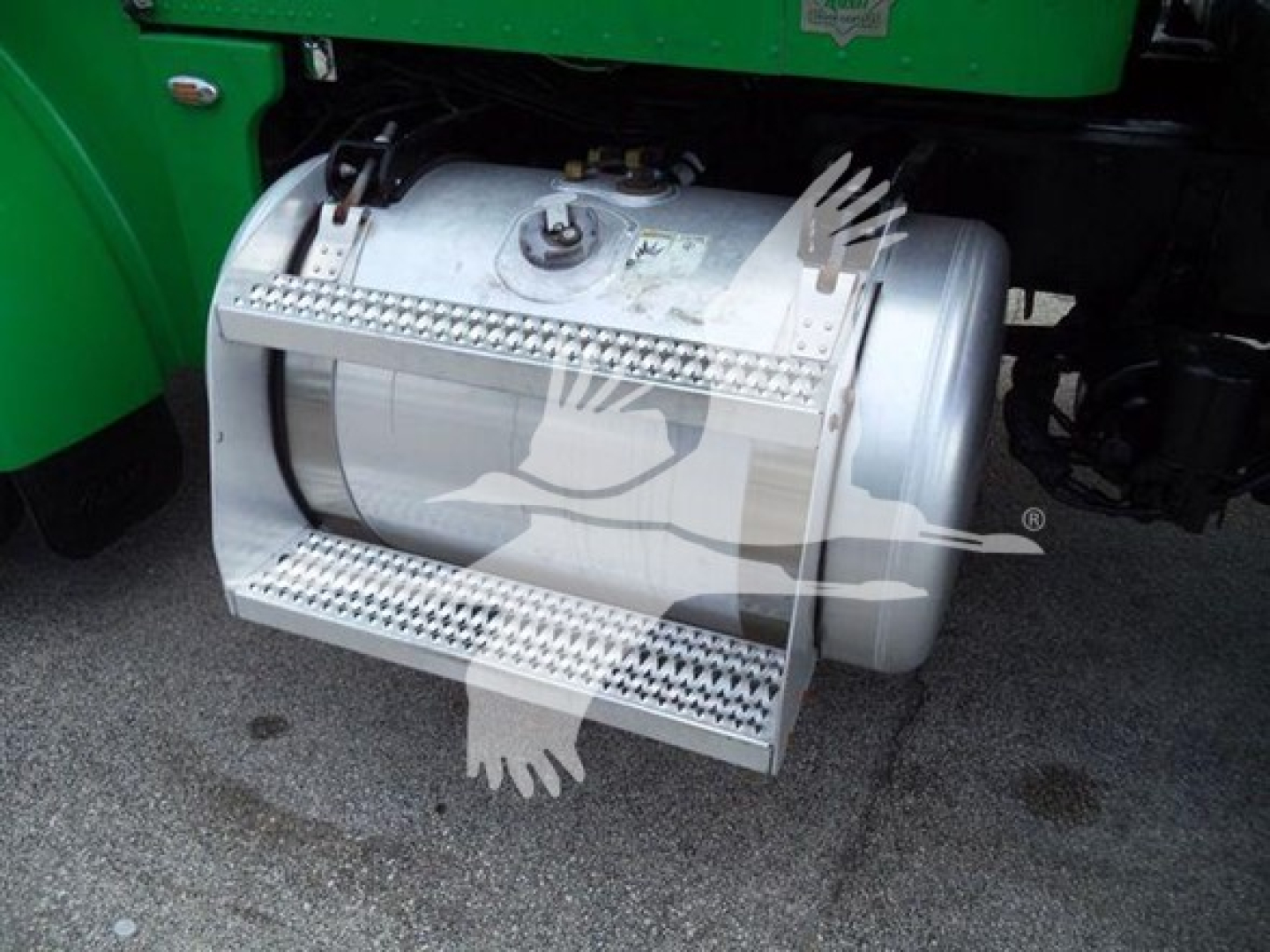Peterbilt truck fuel tank with steps, cylindrical polished aluminum tank mounted under a green cab.